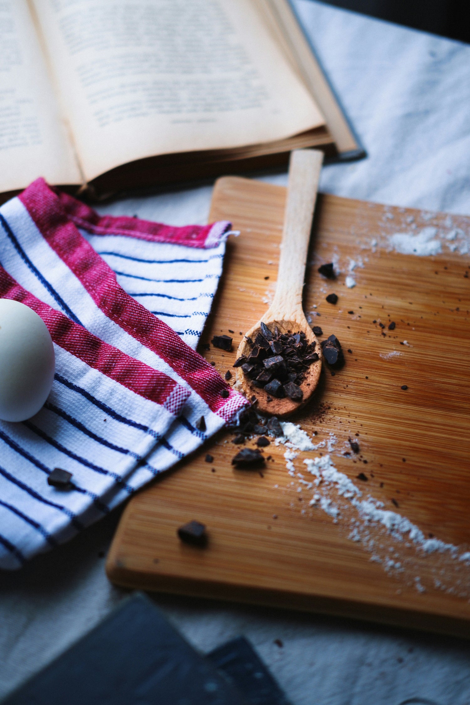 Rustic baking scene with wooden board flour recipe book chocolate pieces eggs and kitchen towel for baking ebooks collection